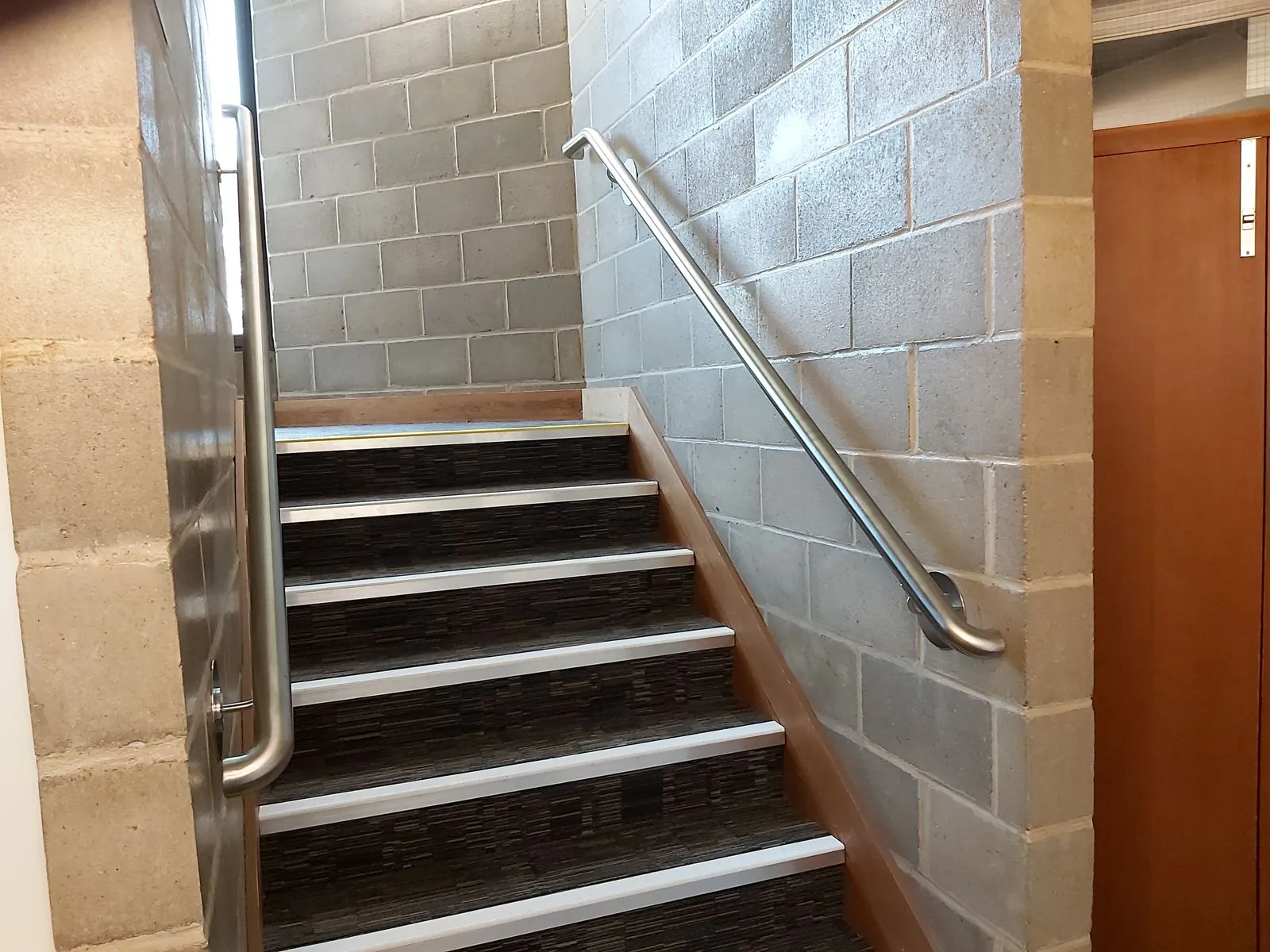 Stainless steel handrails either side of an internal concrete staircase