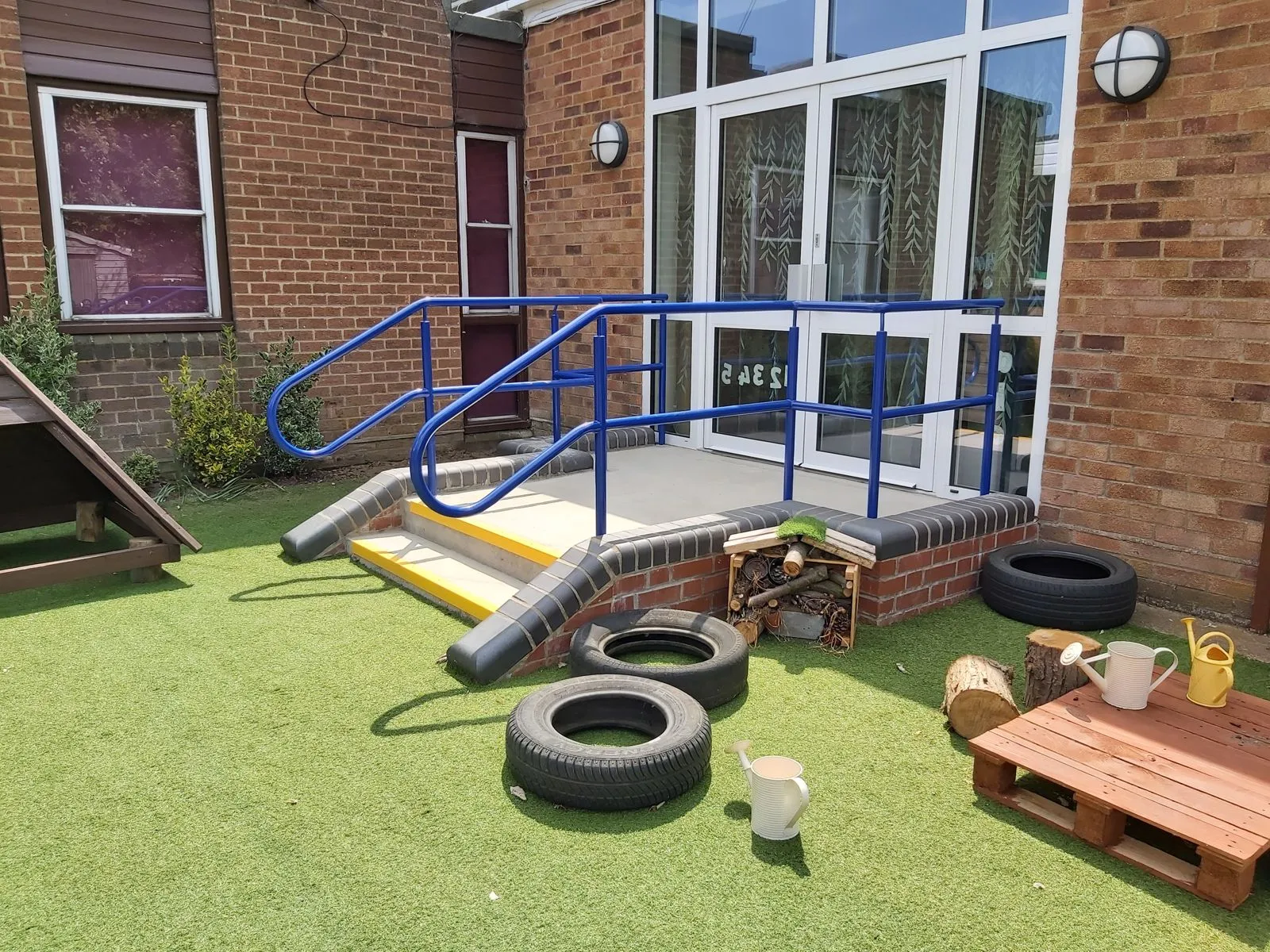 Blue steel handrails on a short access ramp outside a school building