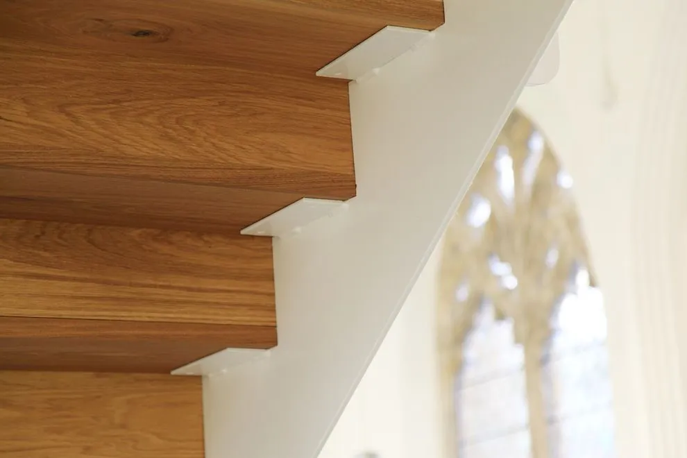Oak stair treads on a white steel stringer against a gothic church window