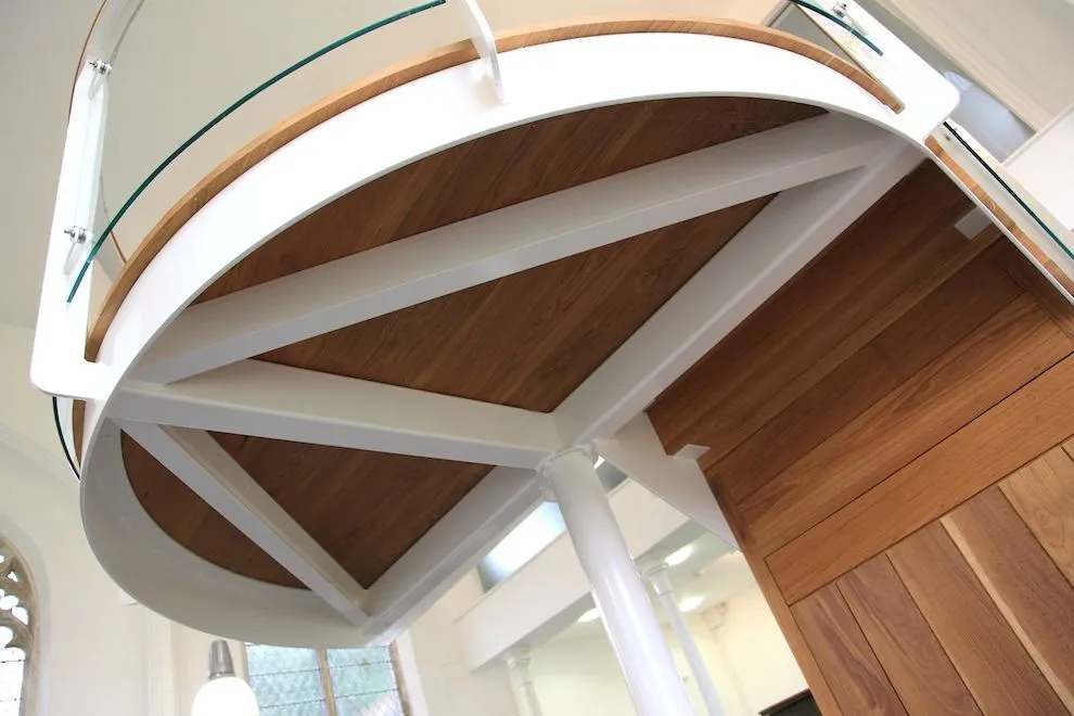 Underside of the curved balcony landing, showing its white steel frame and oak floor