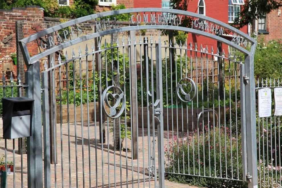 Arched galvanised steel entrance gates with decorative motifs at Grapes Hill Community Garden, Norwich