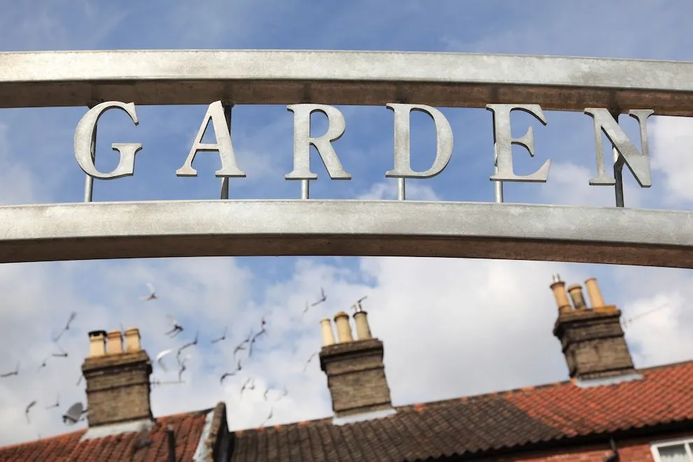 Cut-out steel lettering spelling GARDEN on the arch over the community garden gates