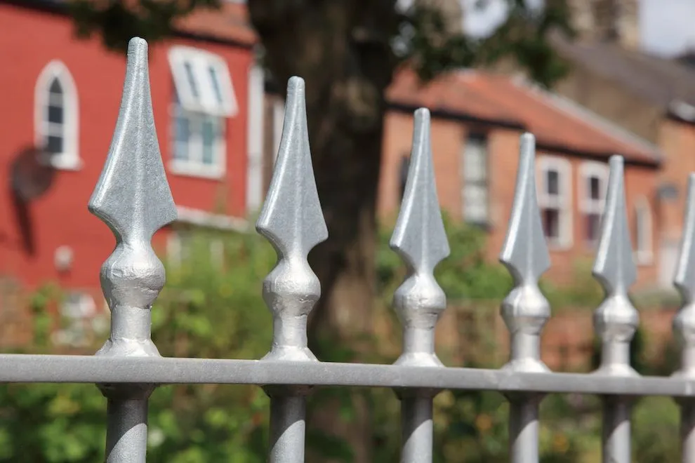 Galvanised railing with spear-head finials in front of red-brick houses