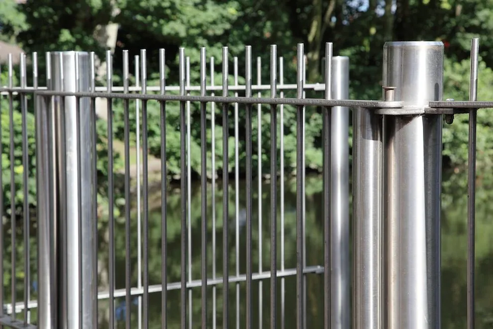 Brushed stainless steel gate posts and vertical bars beside the river in Norwich
