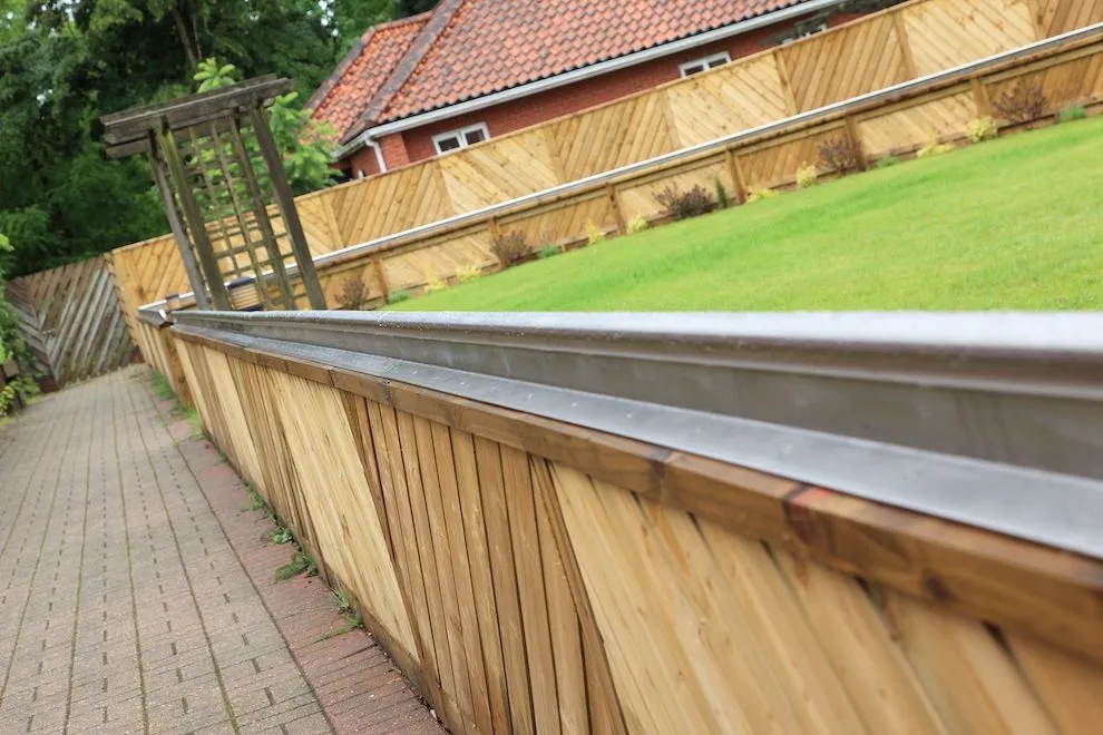 Long stainless steel rail along a timber retaining wall and brick path