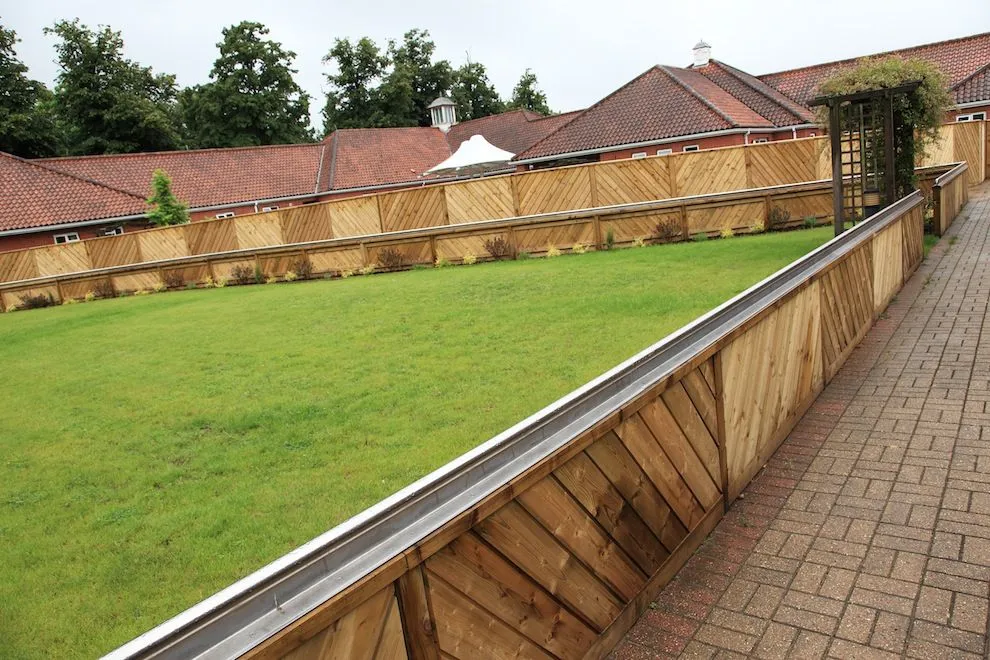 Stainless steel rail running along a timber-clad raised bed beside a lawn