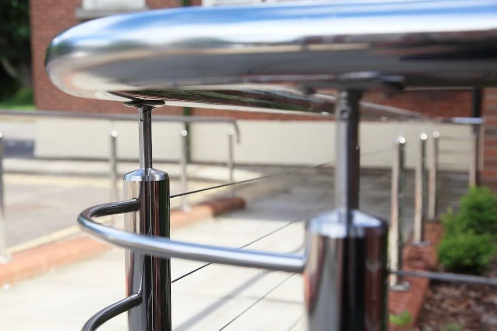Close-up of a polished stainless steel handrail bend and post