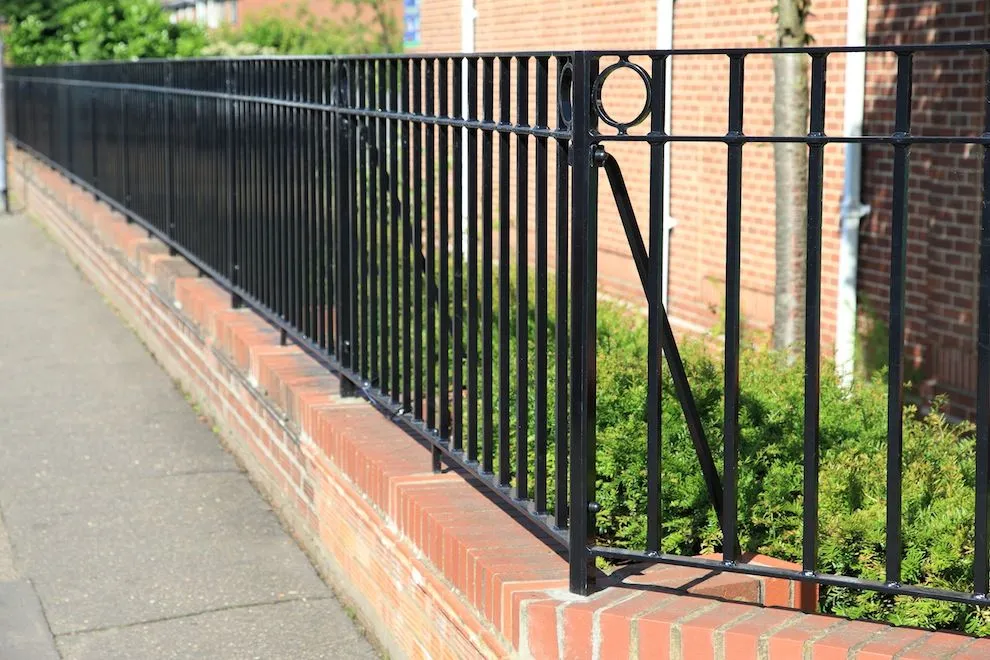Black steel railings on a red-brick wall alongside a footpath