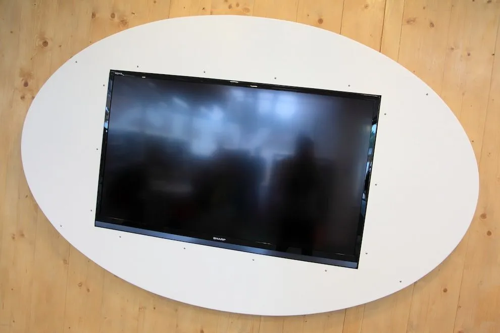 Oval white aluminium surround housing a wall-mounted TV at Blue Bell Academy