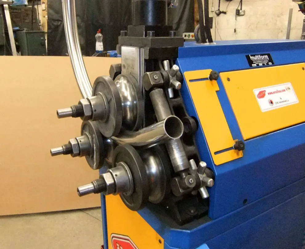 Stainless steel tube being rolled on a blue and yellow section-rolling machine