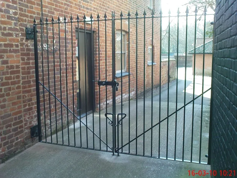 Black steel double gates across an alley between brick buildings