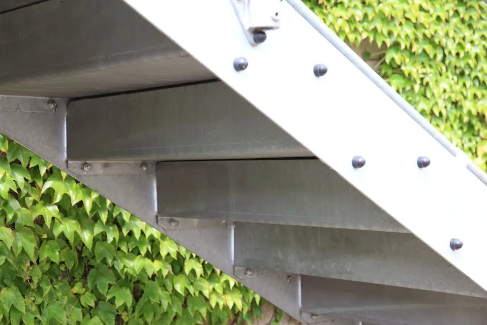 Underside of a galvanised steel staircase showing its bolted stringer