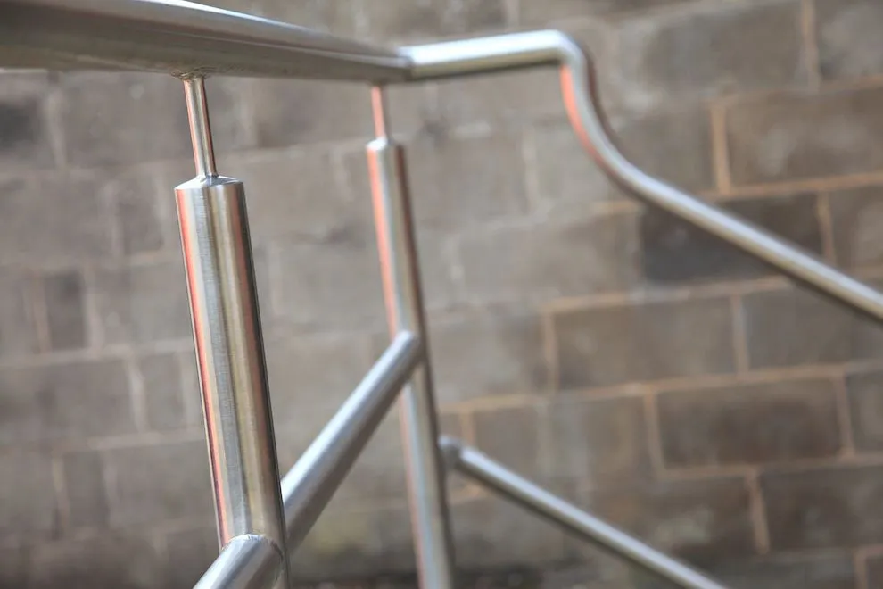 Brushed stainless steel handrail and balustrade against a blockwork wall