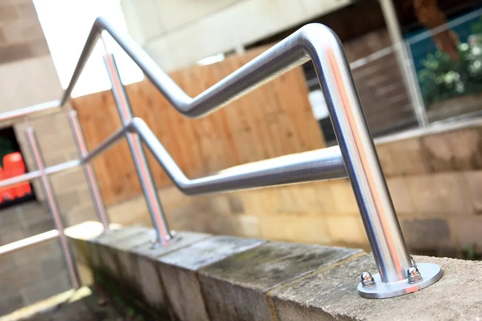 Bent stainless steel handrail fixed to a low wall