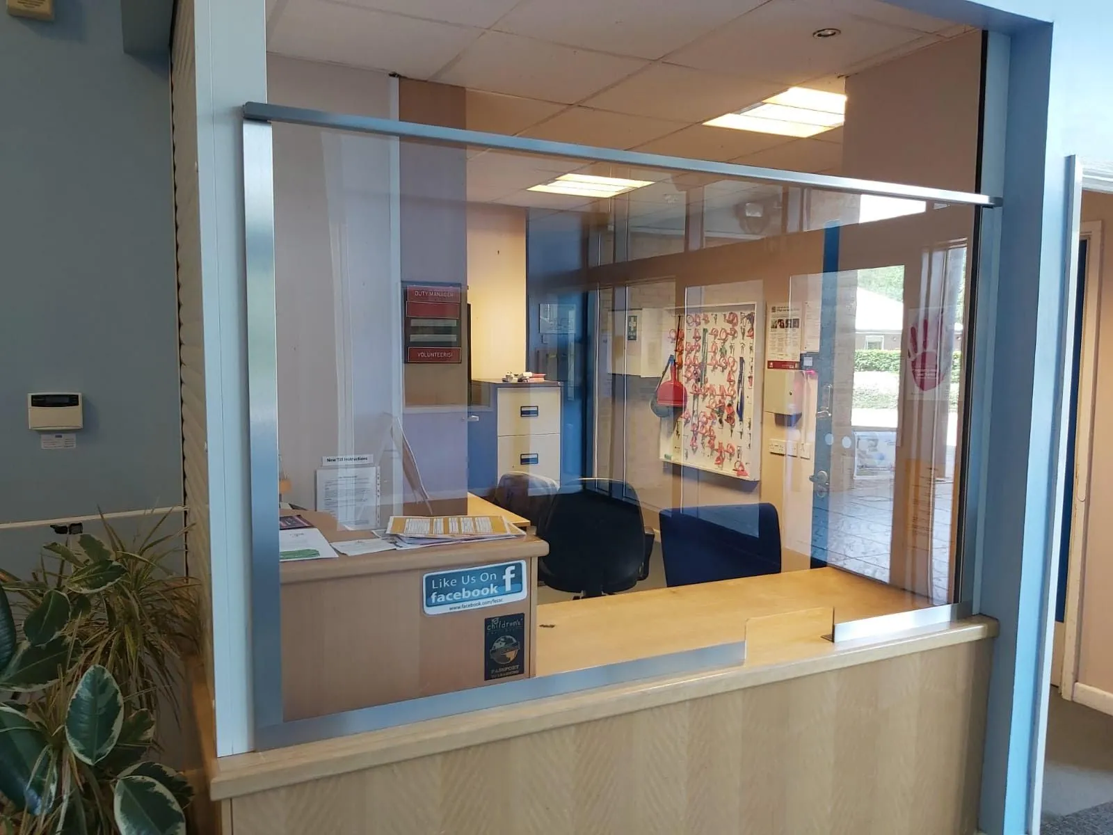 Stainless-framed protection screen across a reception counter