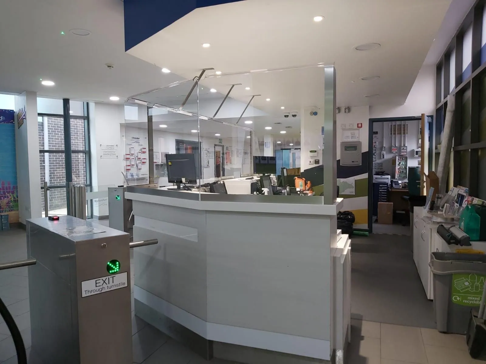 Protection screens on a reception counter beside entry turnstiles