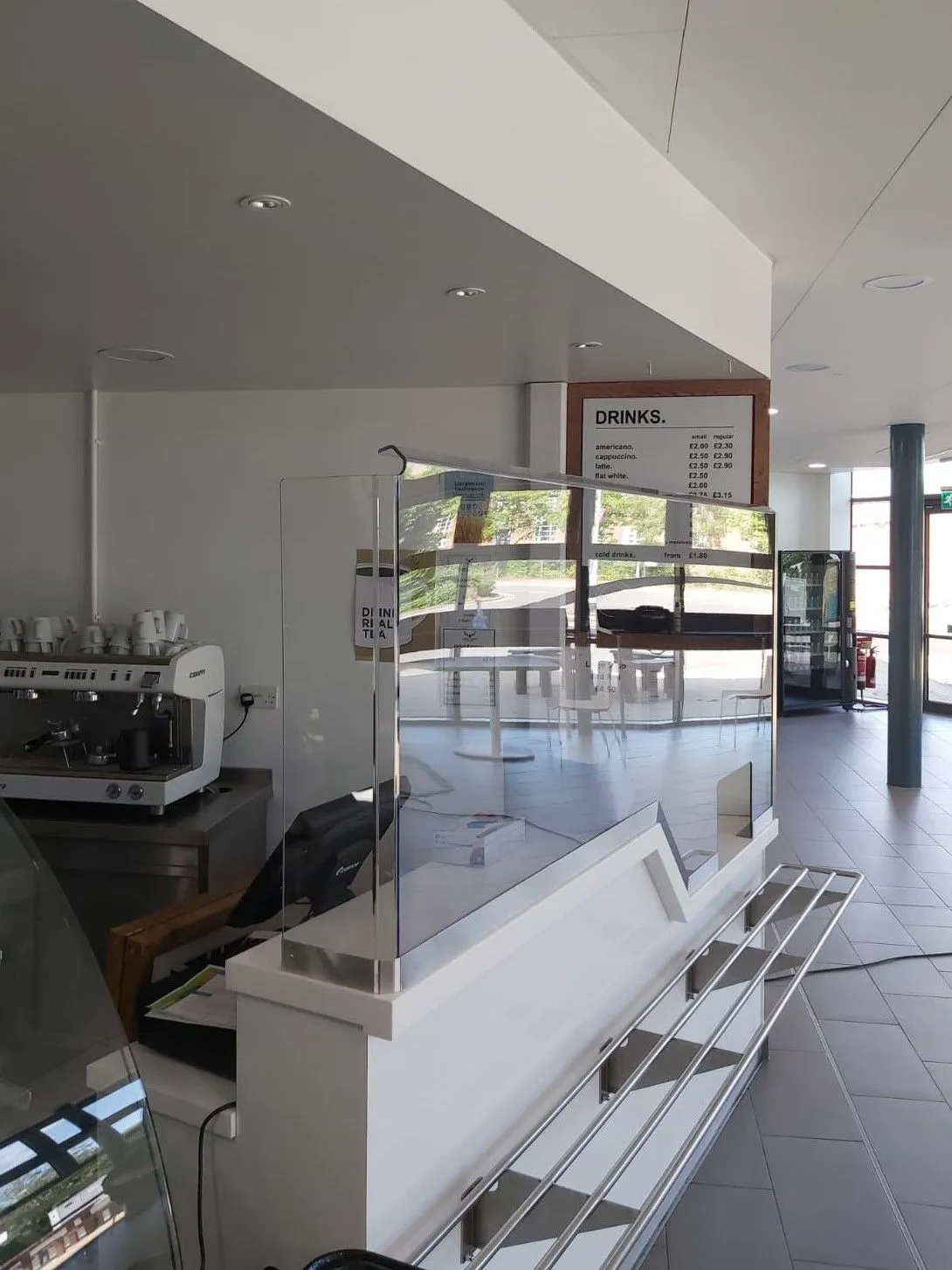 Glass protection screen with a stainless steel frame on a café counter